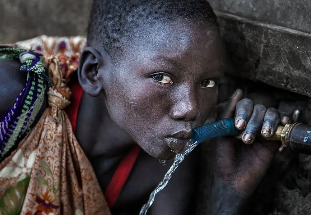 Garmendia, Inazio Joxe: Niña de la tribu Surmi bebiendo agua de un grifo - Etiopía